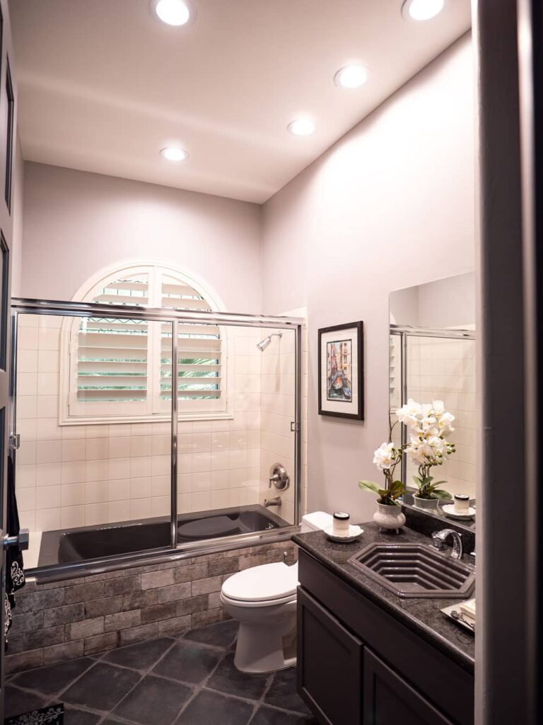 Arched window shutters offer privacy and light in this sleek, modern bathroom.