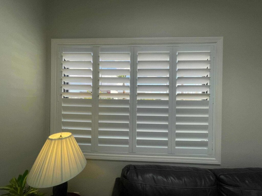 Four-panel white plantation shutters provide excellent light control and privacy in the room.