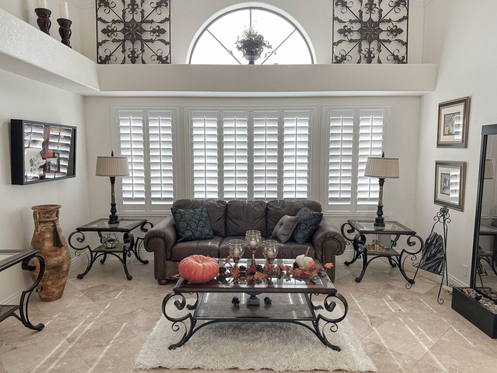 White living room shutters create a bright backdrop for cozy fall decor and sophisticated style.