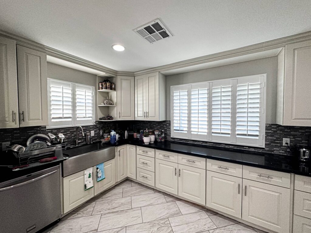 Brighten your cooking space with classic white kitchen shutters against a dark backsplash.