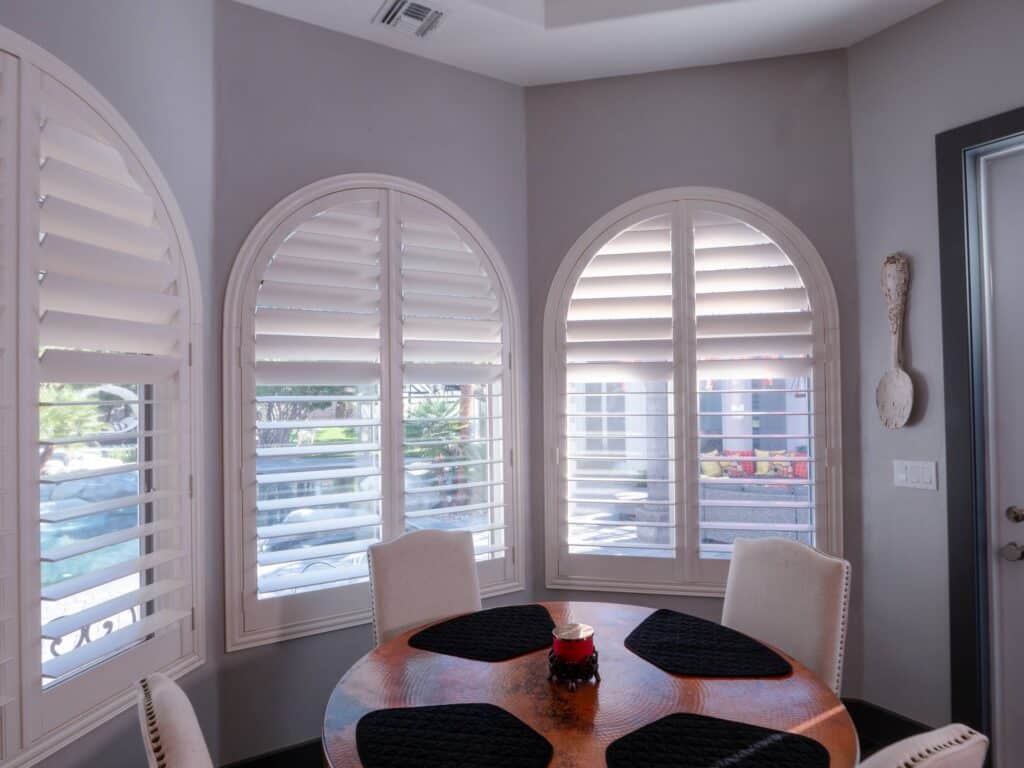 Custom arched dining room shutters provide privacy with a view of the beautiful pool!